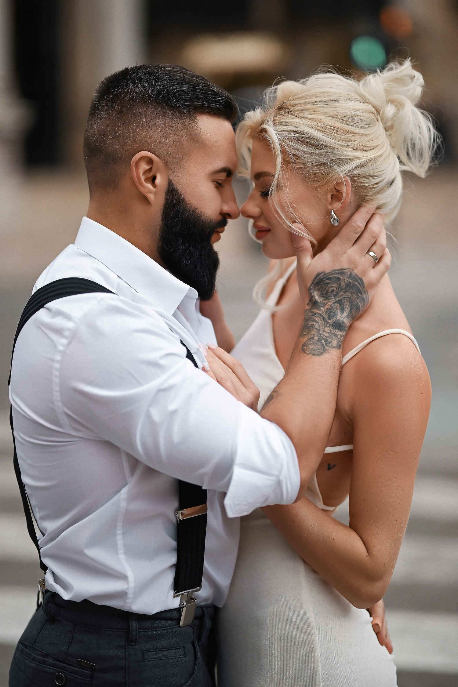 Close-up portrait of a bold couple looking into each other's eyes, featuring a tattooed hand. Edgy urban photography in Valencia center