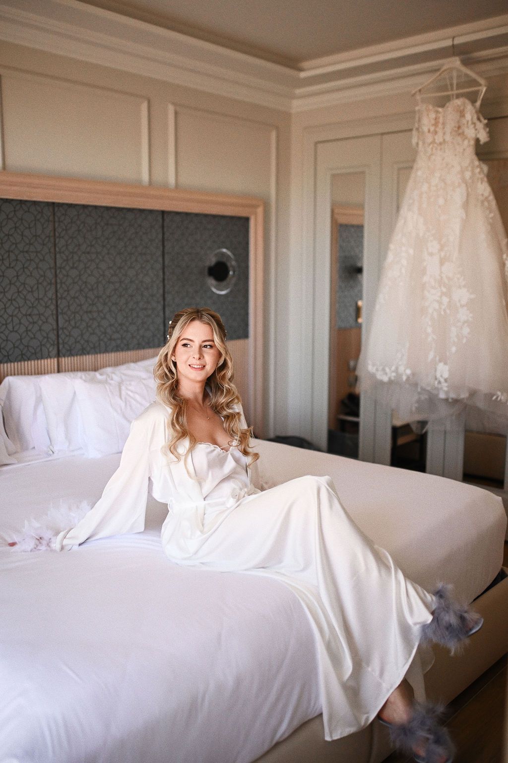 Editorial portrait of the bride posing in front of her wedding dress at Barcelo La Nucia Palms hotel before the Benidorm ceremony.