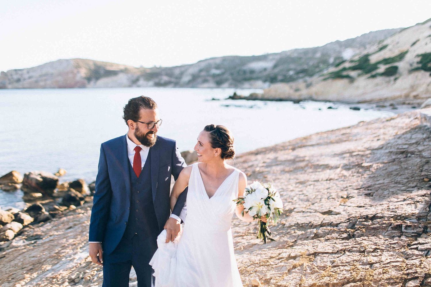 Romantic stroll of the bride and groom on a secluded beach during sunset