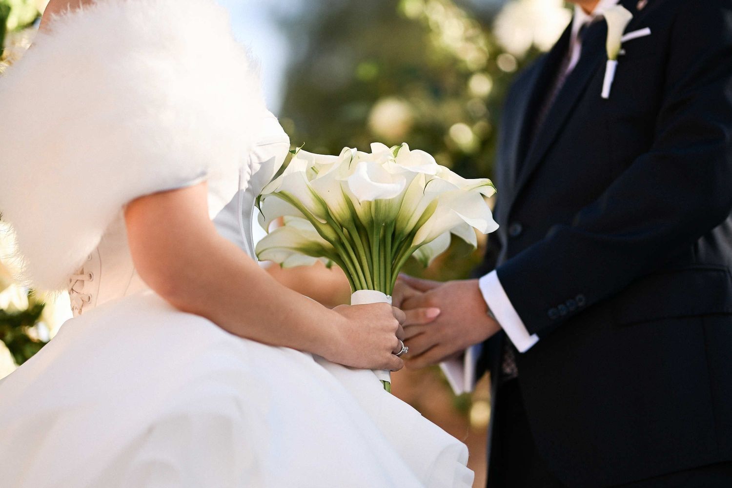 Close-up of a minimalist Calla Lily wedding bouquet and the couple's hands, capturing the documentary essence of their Valencia wedding.