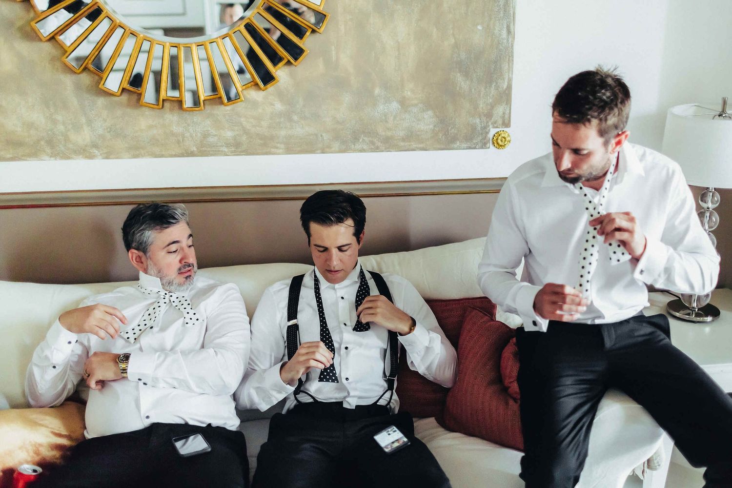 A fun and authentic moment of the groom and his friends learning to tie a bowtie. Captured by a destination wedding photographer in Spain