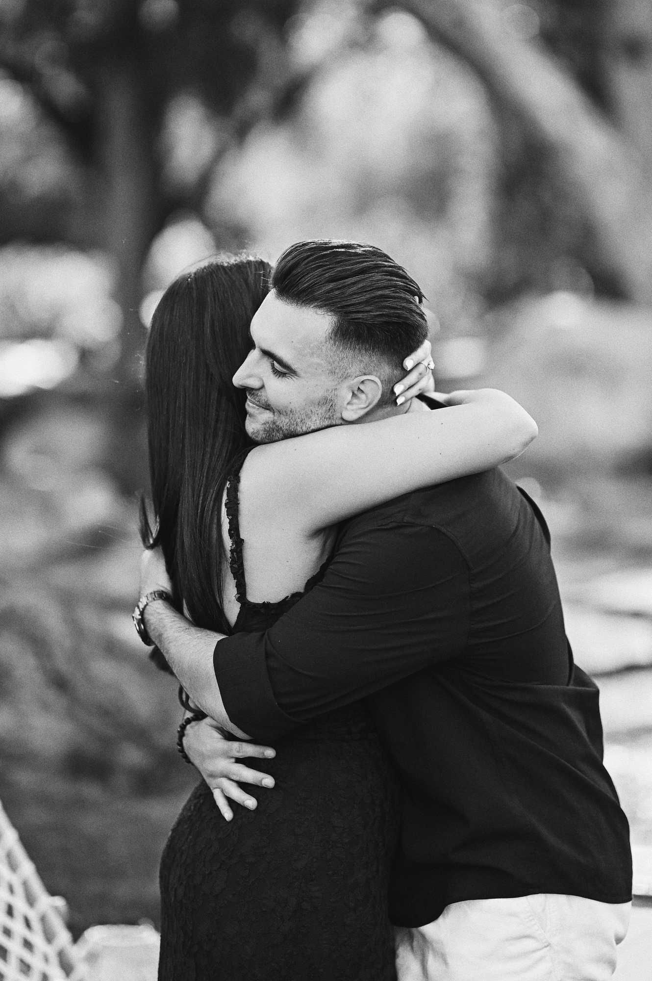 Black and white portrait of a couple sharing a tight, emotional hug right after their marriage proposal in Jardin del Real.