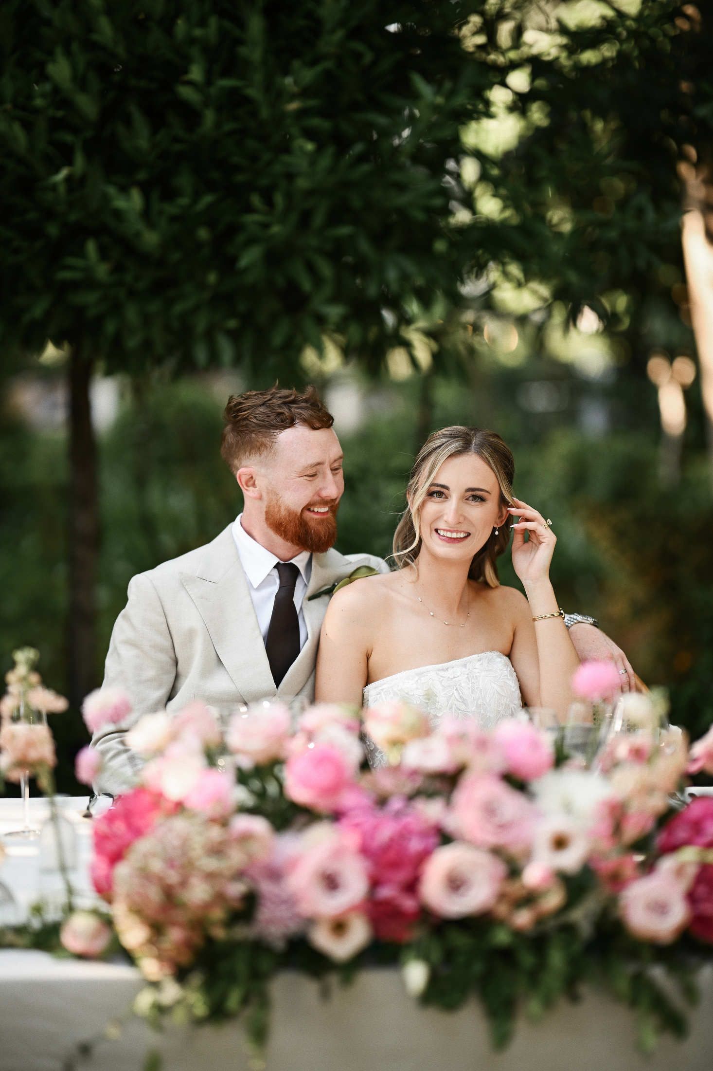 Happy newlyweds sitting together at their beautifully decorated head table during the wedding dinner at Villa Dela.