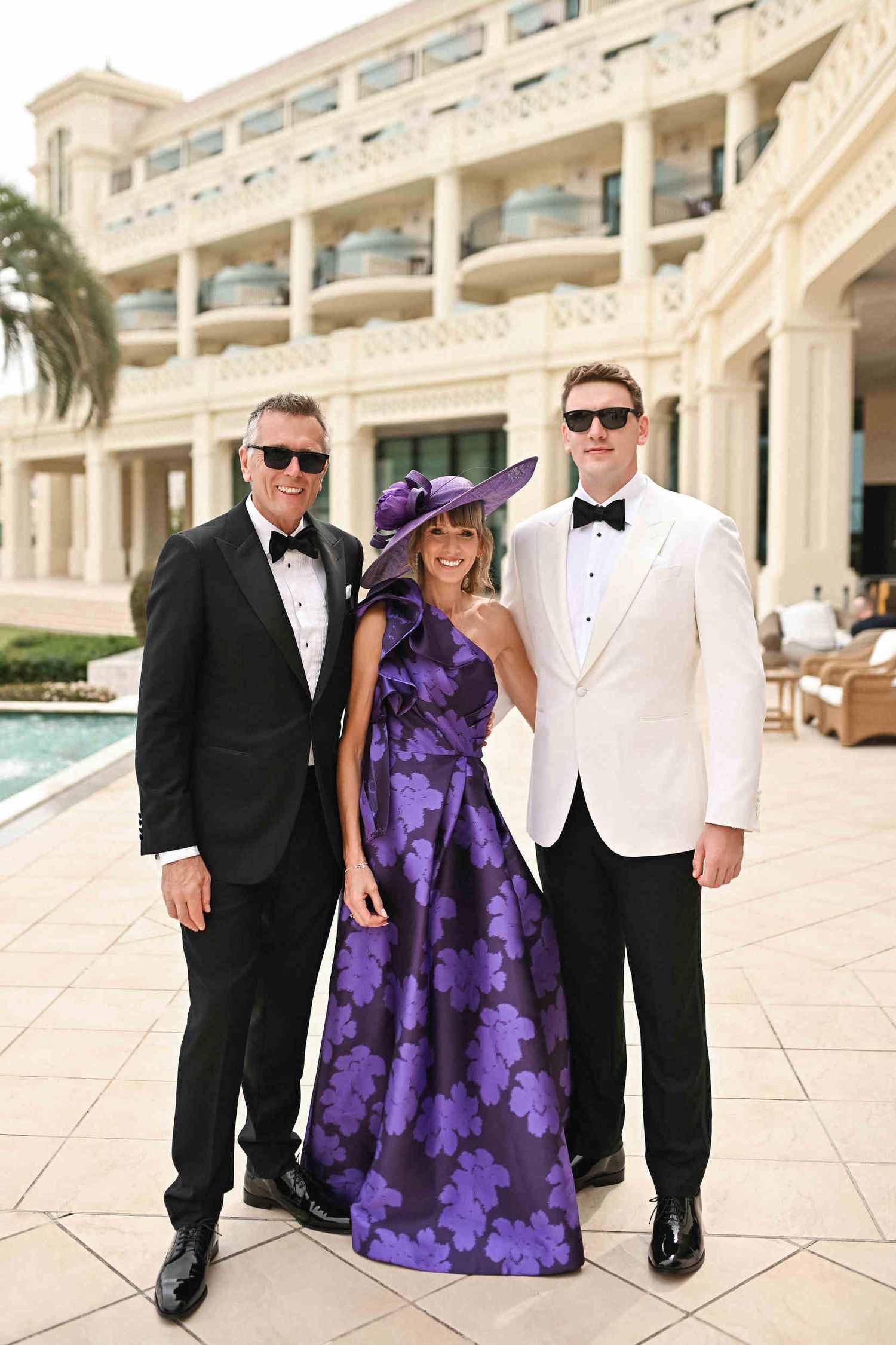Wedding guests in a purple floral dress and white tuxedo posing together at Hotel Las Arenas Valencia