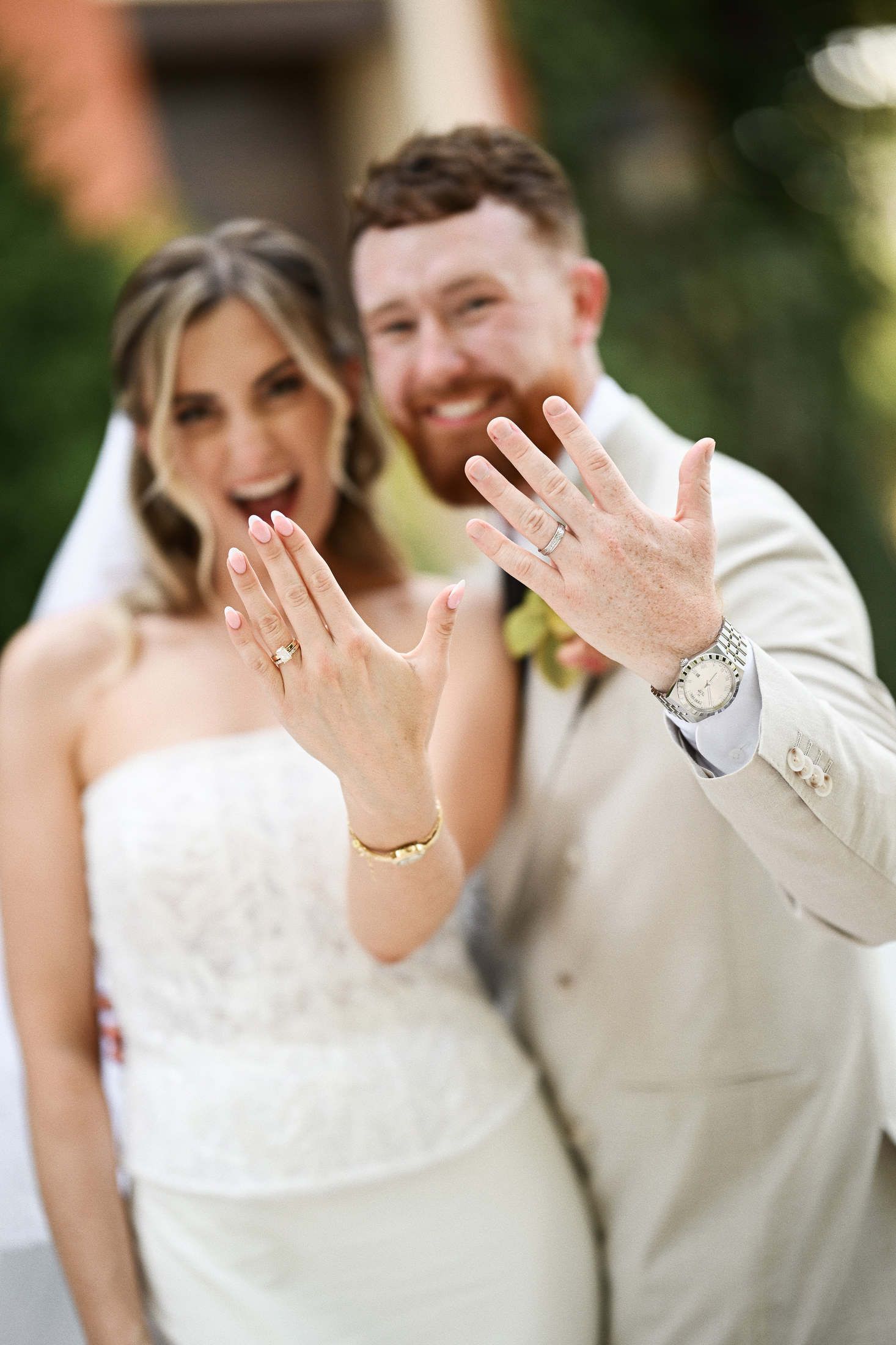 Happy newlyweds smiling and showing their wedding rings close-up to the camera right after the ceremony in Valencia.