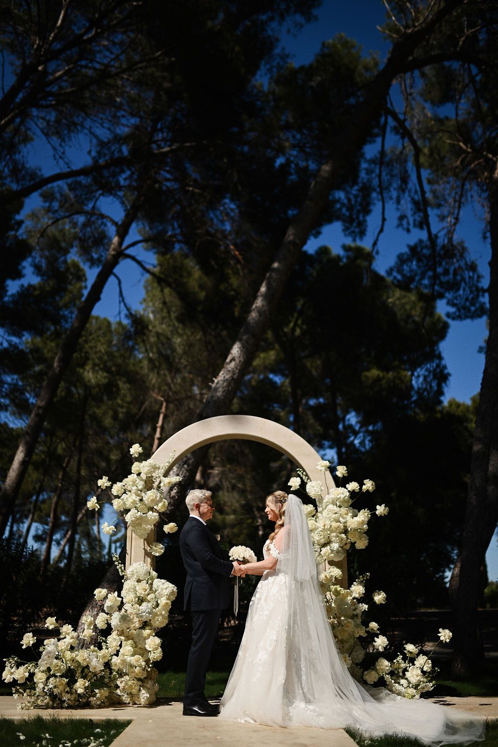 Wedding ceremony at El Bosque in Finca El Senyoret. The couple standing by the stone arch for a scenic Benidorm destination wedding.
