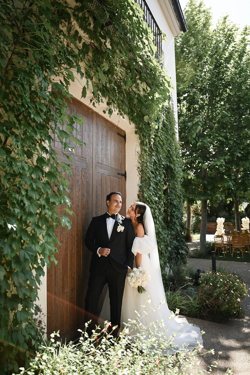 The bride and groom posing against the massive historic wooden doors of Finca del Canónigo, a luxury destination venue in Spain.