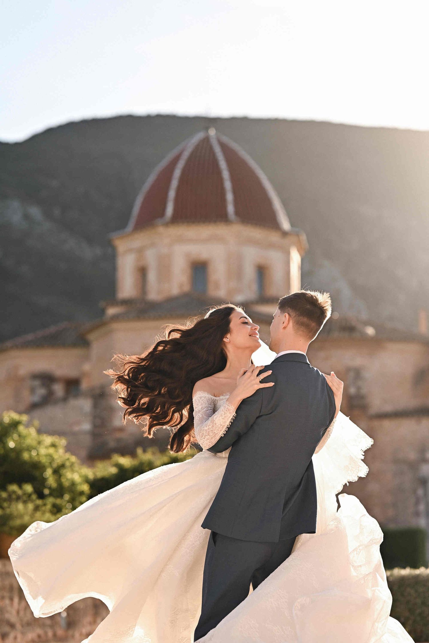 Groom spinning the bride, her Hollywood waves hairstyle flowing with movement at the historic Monasterio