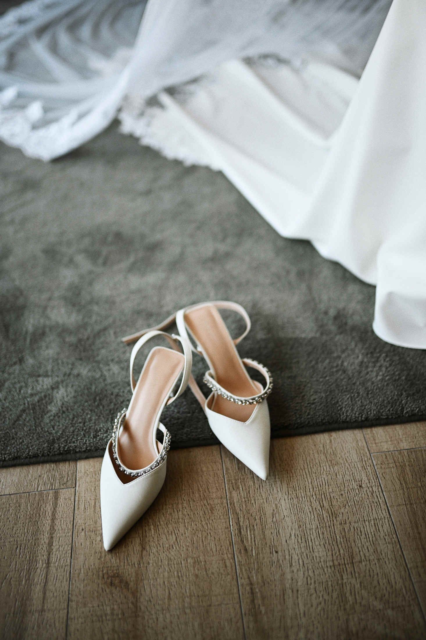 Close-up shot of stylish bridal shoes and a delicate wedding veil, fine art morning details of the bride.
