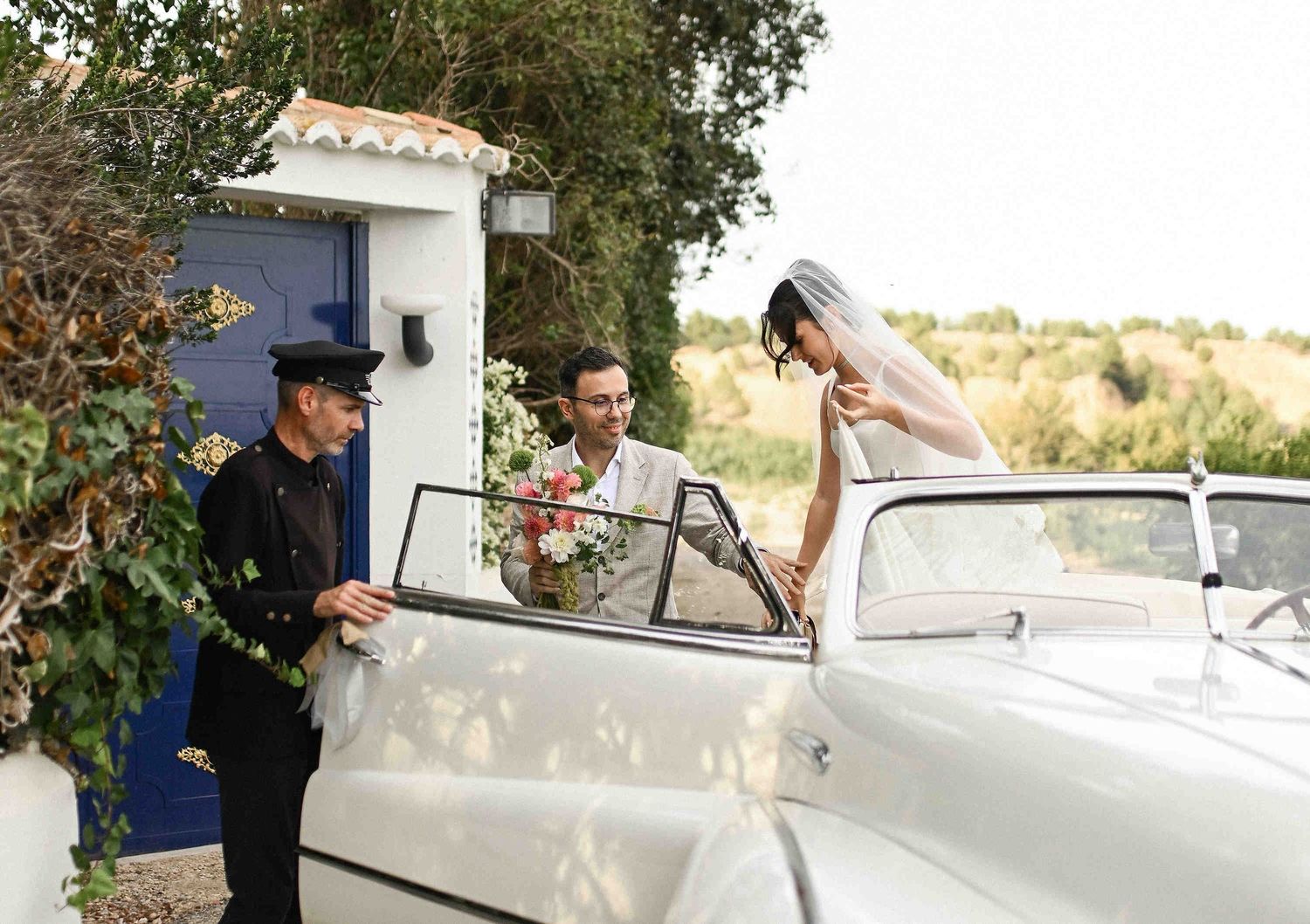 Stylish arrival in a vintage car with a driver for a luxury destination wedding framed through the lens of a Valencia-based artist