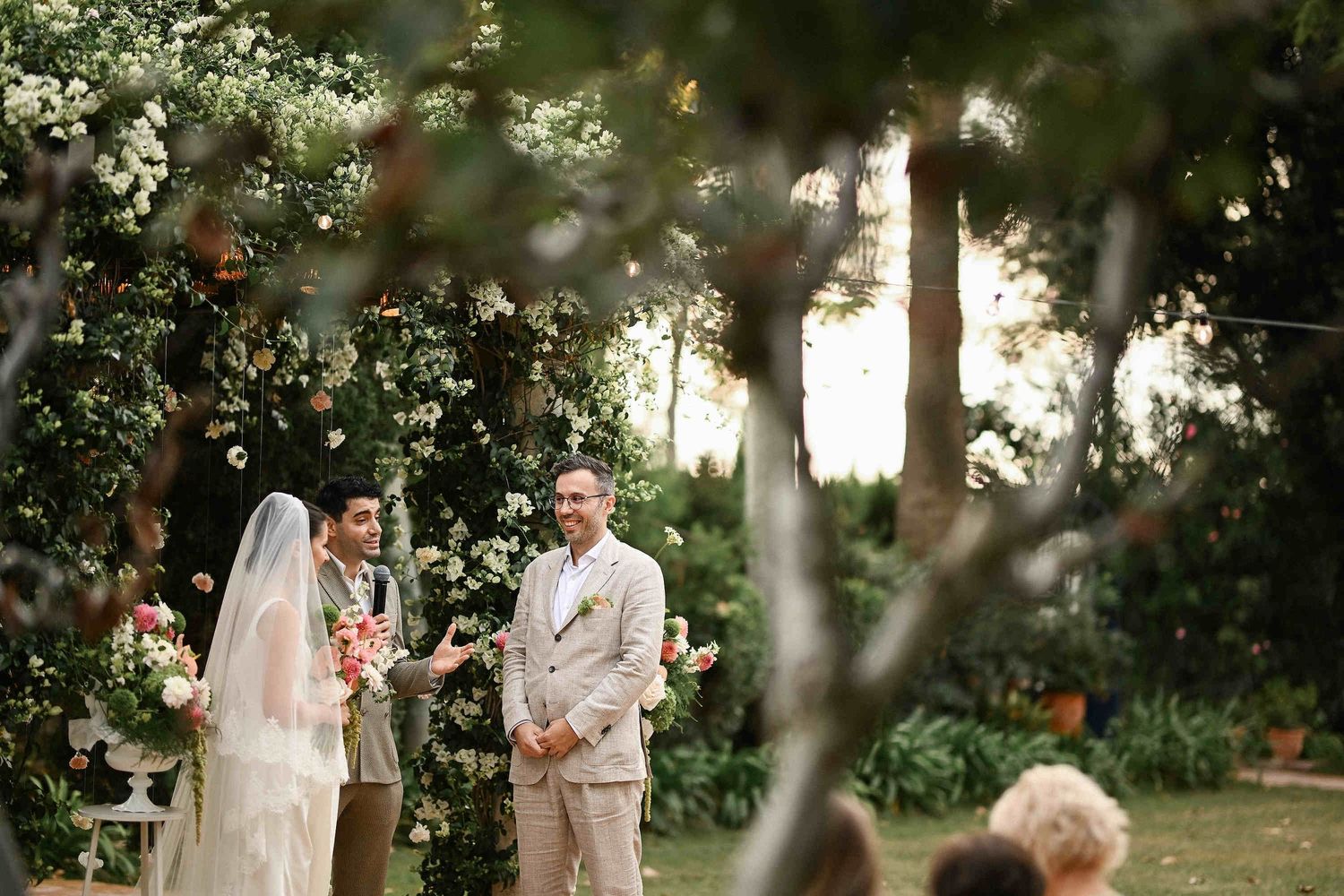 The bride and groom looking at their guests during the signing ceremony in front of the floral arch