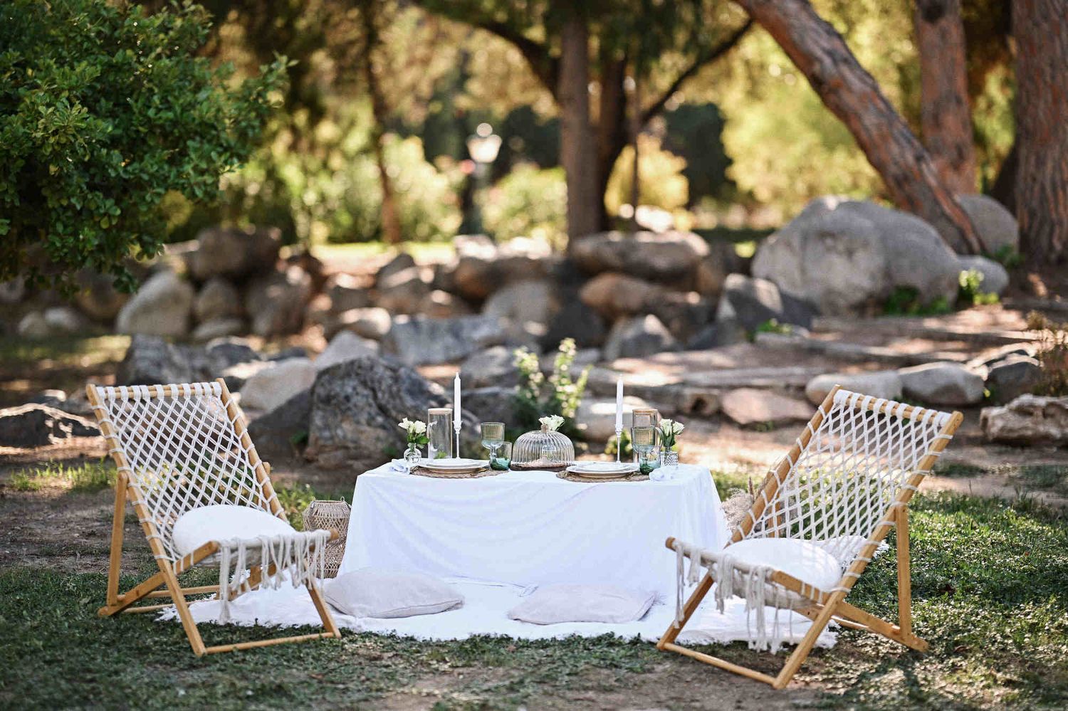 Romantic surprise proposal picnic setup with woven chairs and candles under trees in Viveros Park.