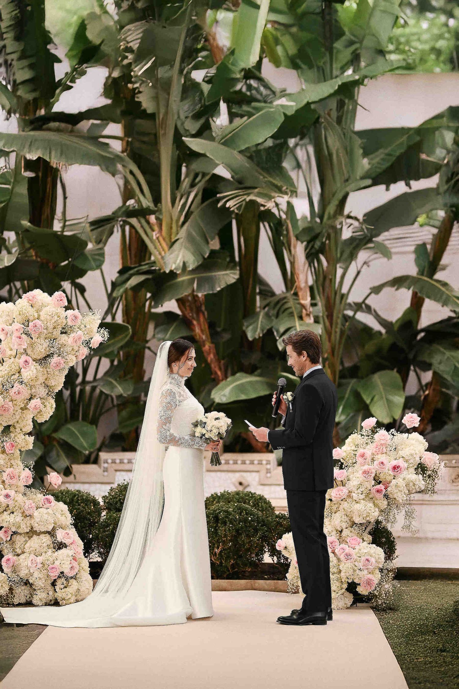 Destination wedding ceremony in Spain set against a dramatic backdrop of lush, vibrant greenery in a beautiful outdoor garden setting