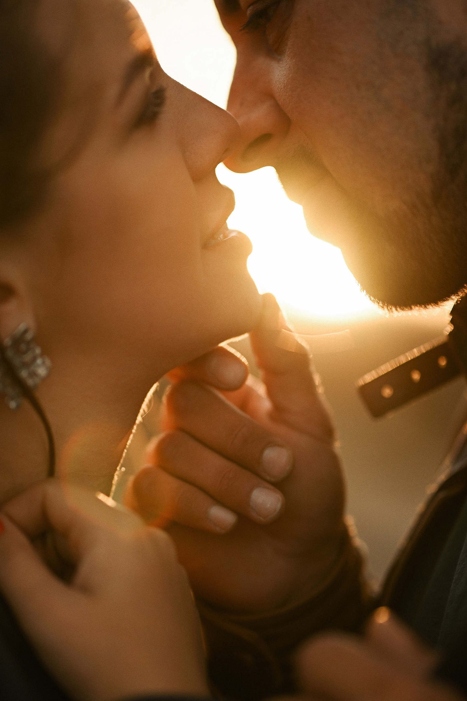 Cinematic close-up portrait of a couple a second before kissing at sunset on the Mediterranean Valencian beach during surprise proposal