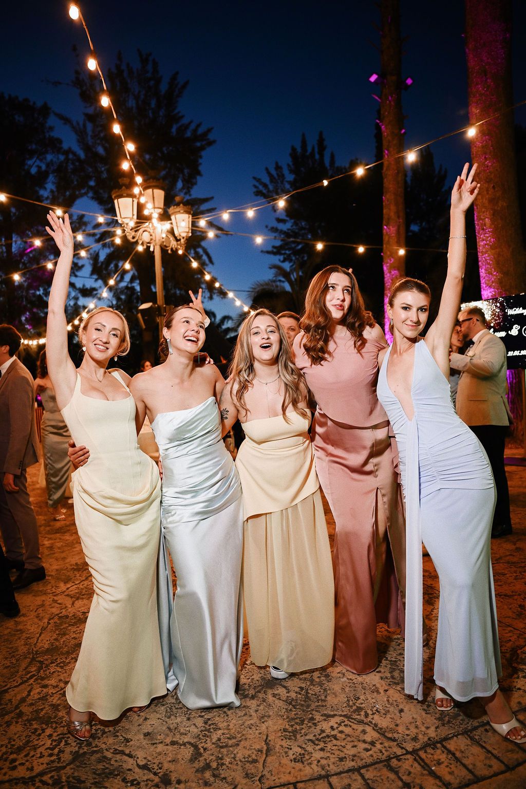 Bridesmaids having fun and singing at the outdoor dinner party. Dynamic direct-flash wedding photography in Benidorm by Darista.