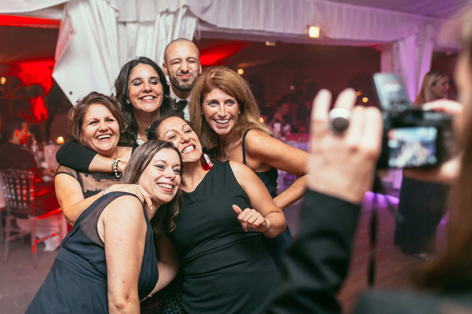 Group of wedding guests taking a mass selfie with an Instax camera. Fun reportage moment captured by a European photographer.