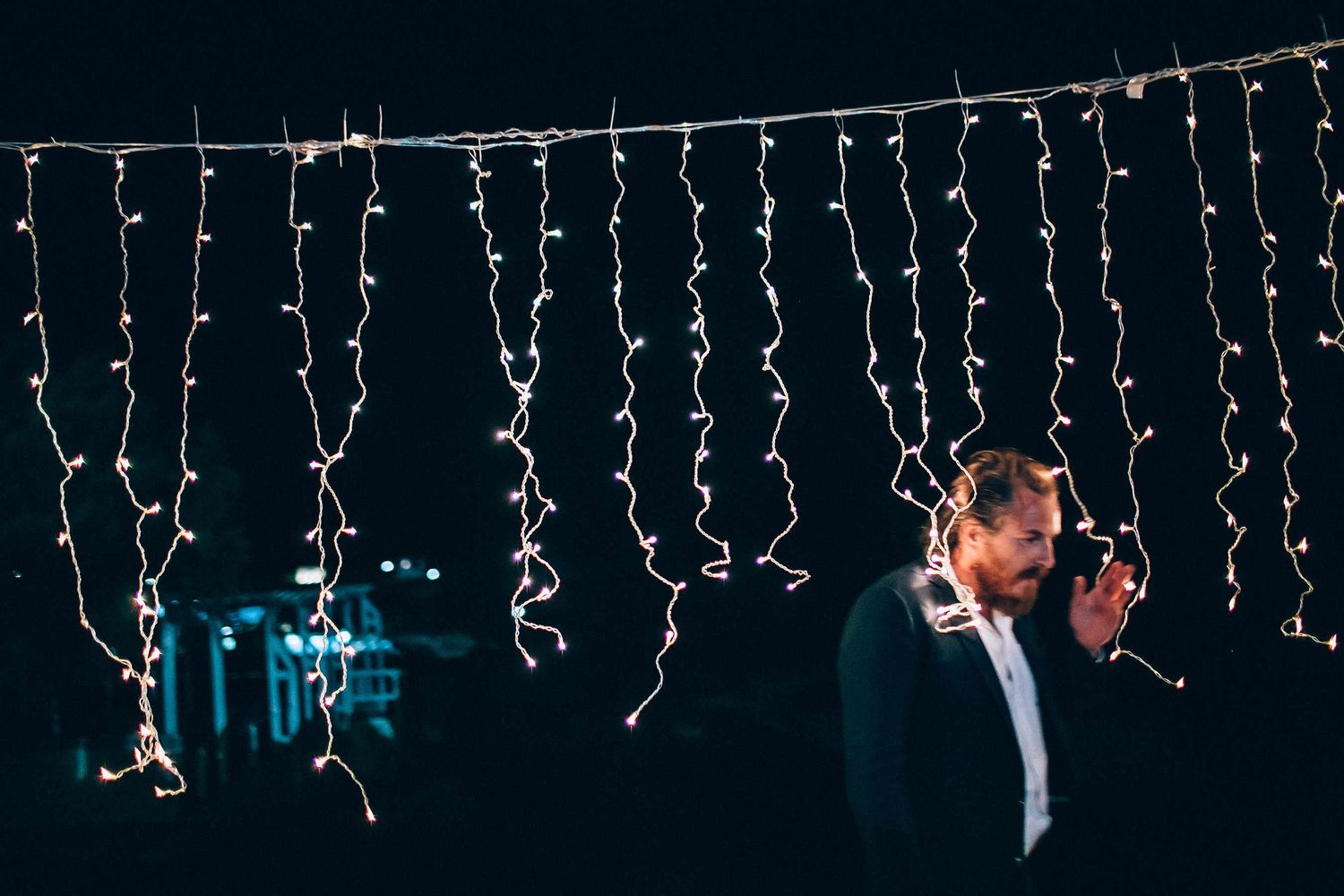 Artistic motion blur photography of a wedding guest moving through string lights at night