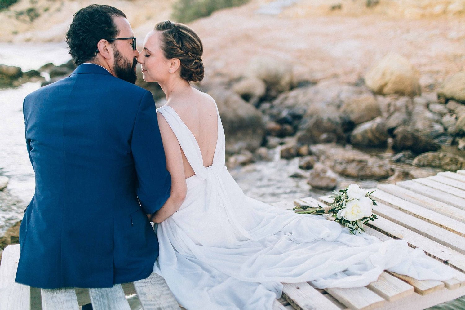 Peaceful moment of the bride and groom sitting on a pier during the Greek sunset
