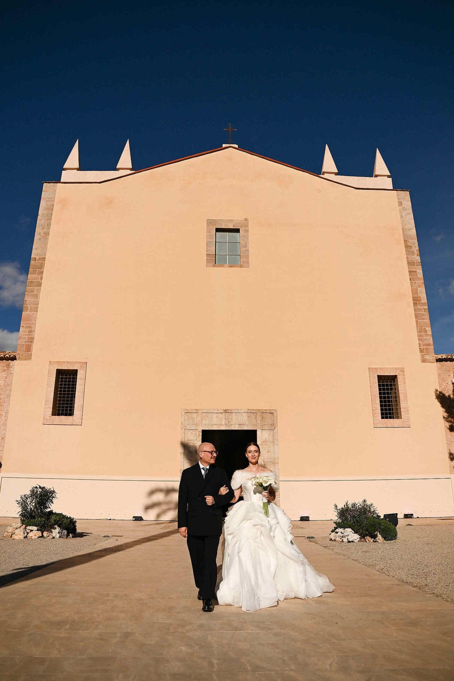 Moving moment of a father walking his daughter down the aisle during a majestic ceremony at La Cartoixa d'Ara Christi, Valencia.
