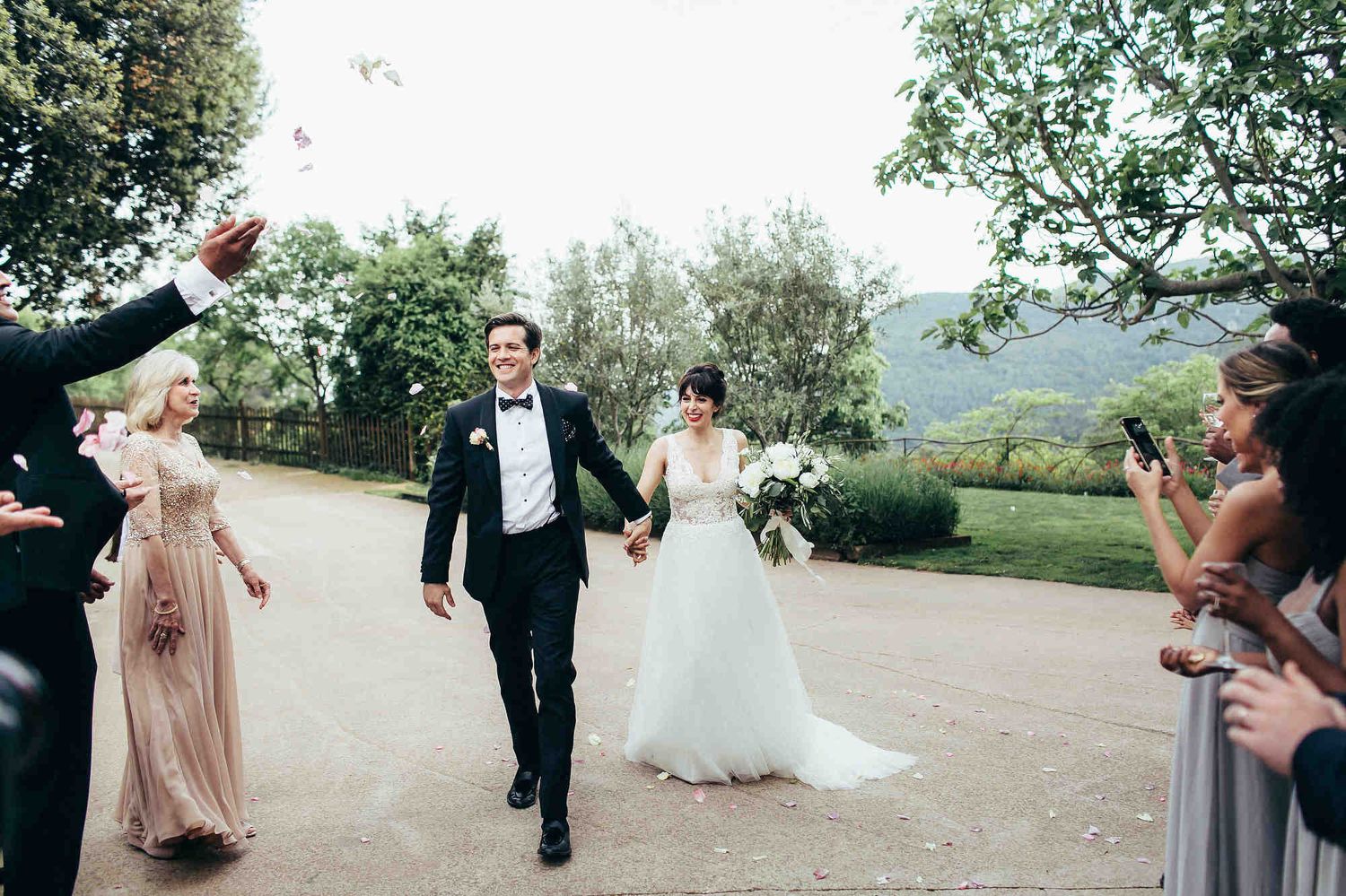 Bride and groom walking through a corridor of guests at a luxury Barcelona villa banquet after an editorial session in Spain.