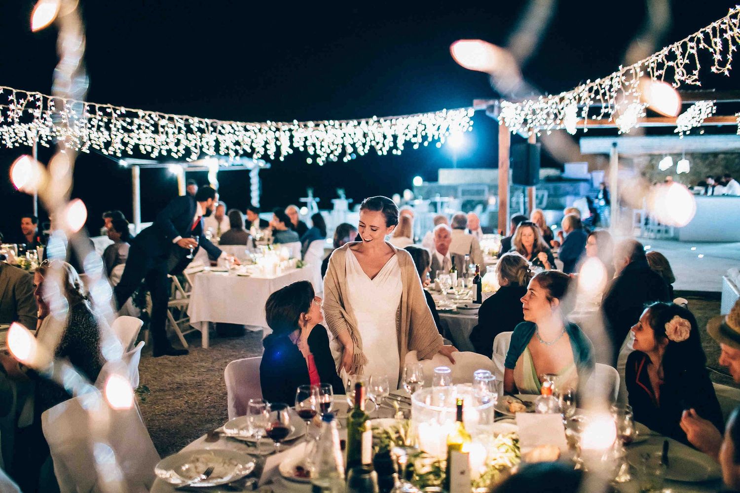The bride sharing a laugh and talking with her guests at their table during the party