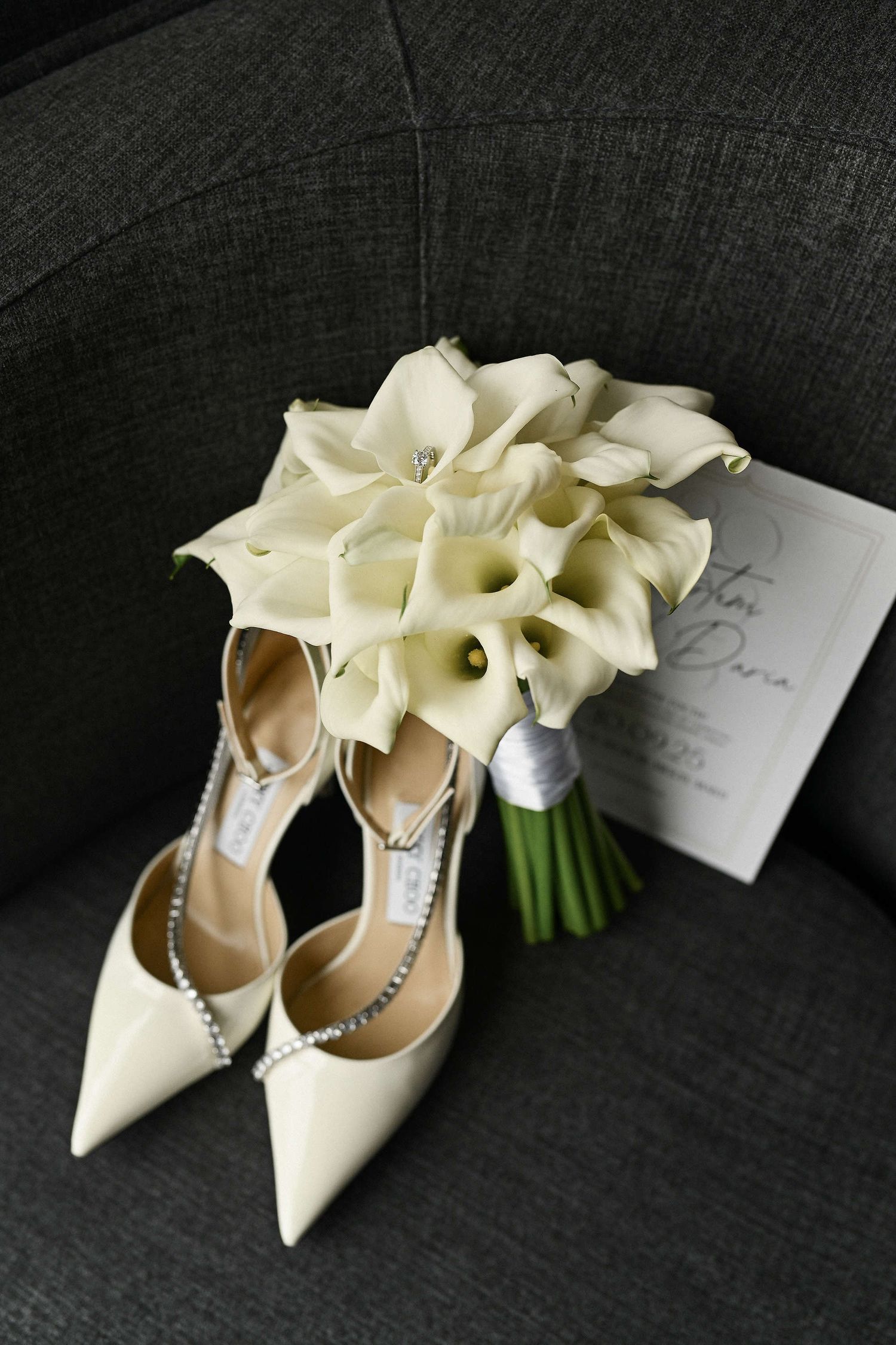 Luxury wedding details: Jimmy Choo shoes, calla lily bouquet, and invitations in a cinematic setting.