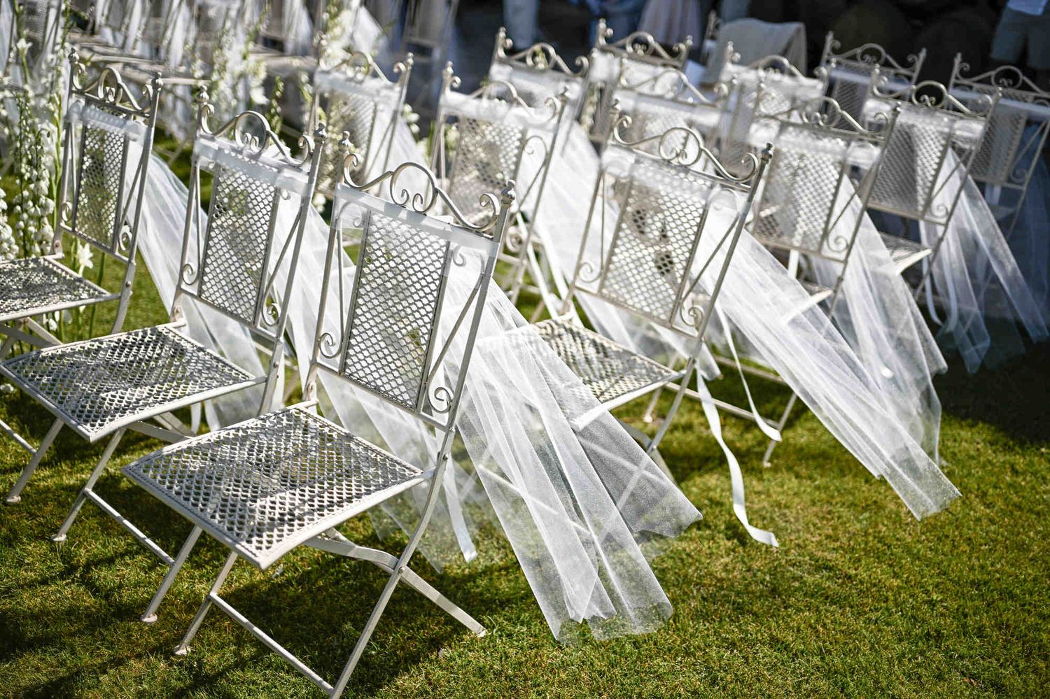 Outdoor wedding ceremony setup with white decorated chairs