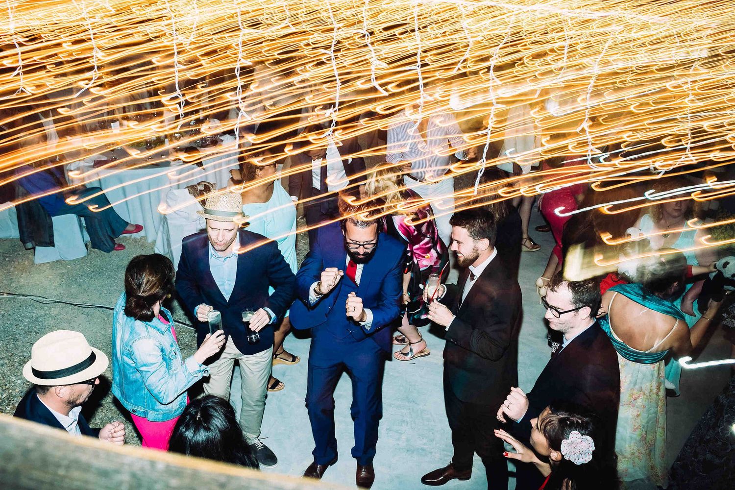 Energetic documentary shot of the groom dancing and celebrating with his friends at the party
