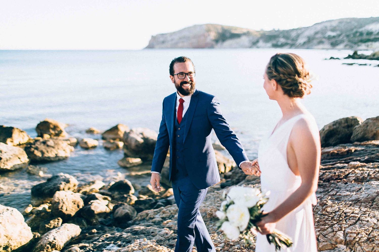 Candid moment of the couple smiling and sharing a laugh during their coastal walk