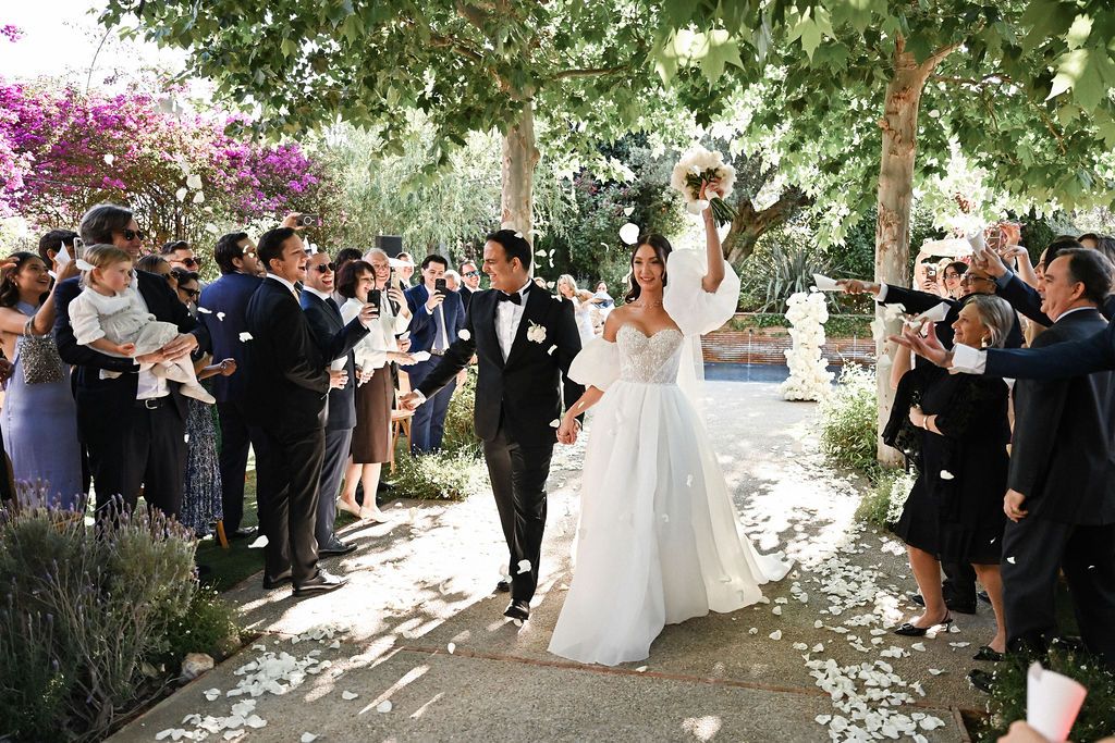 Wide shot of the wedding ceremony exit with guests throwing petals at the bride and groom in the historic Finca del Canónigo estate.