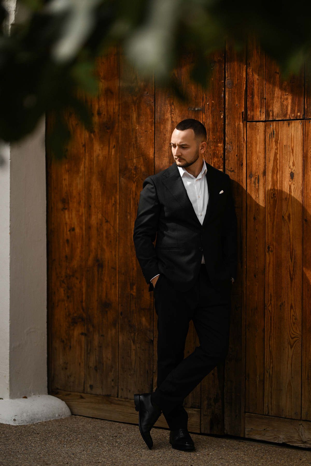 Groom portrait in front of the textured wooden gates at El Telar. Moody, fashion-forward wedding aesthetics by Darista team.