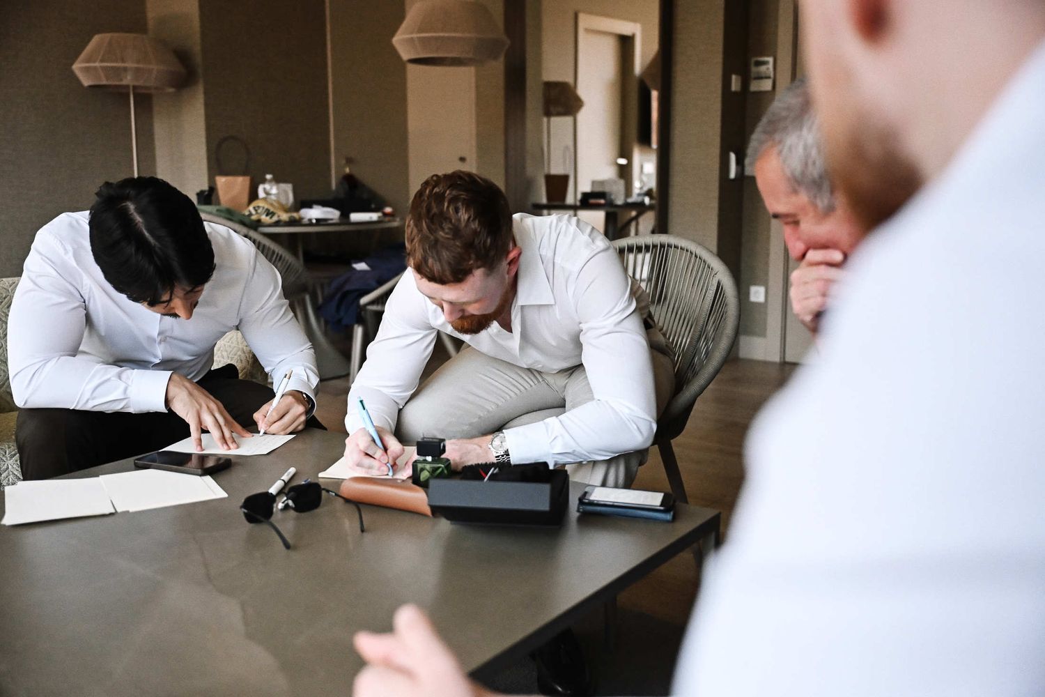 Groom and his best man sitting together and writing wedding speeches for the reception dinner in a Valencia hotel room