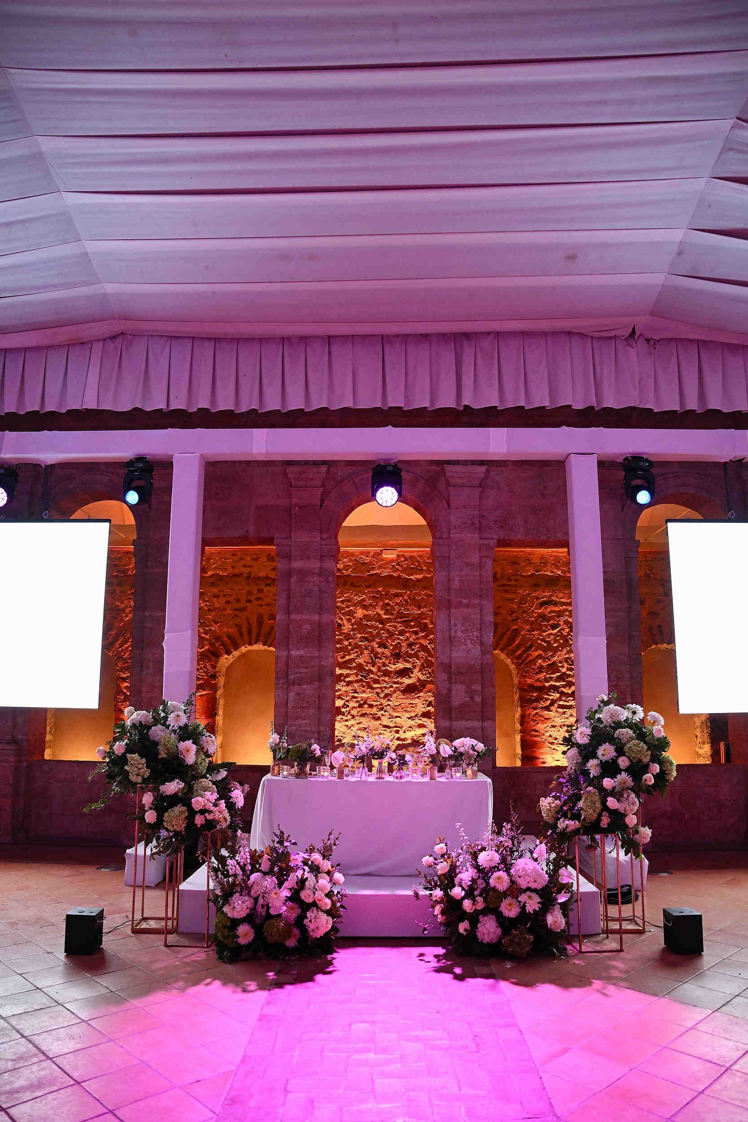 Exquisite head table decor and floral arrangements in the grand banquet hall of La Cartoixa d'Ara Christi, Valencia.