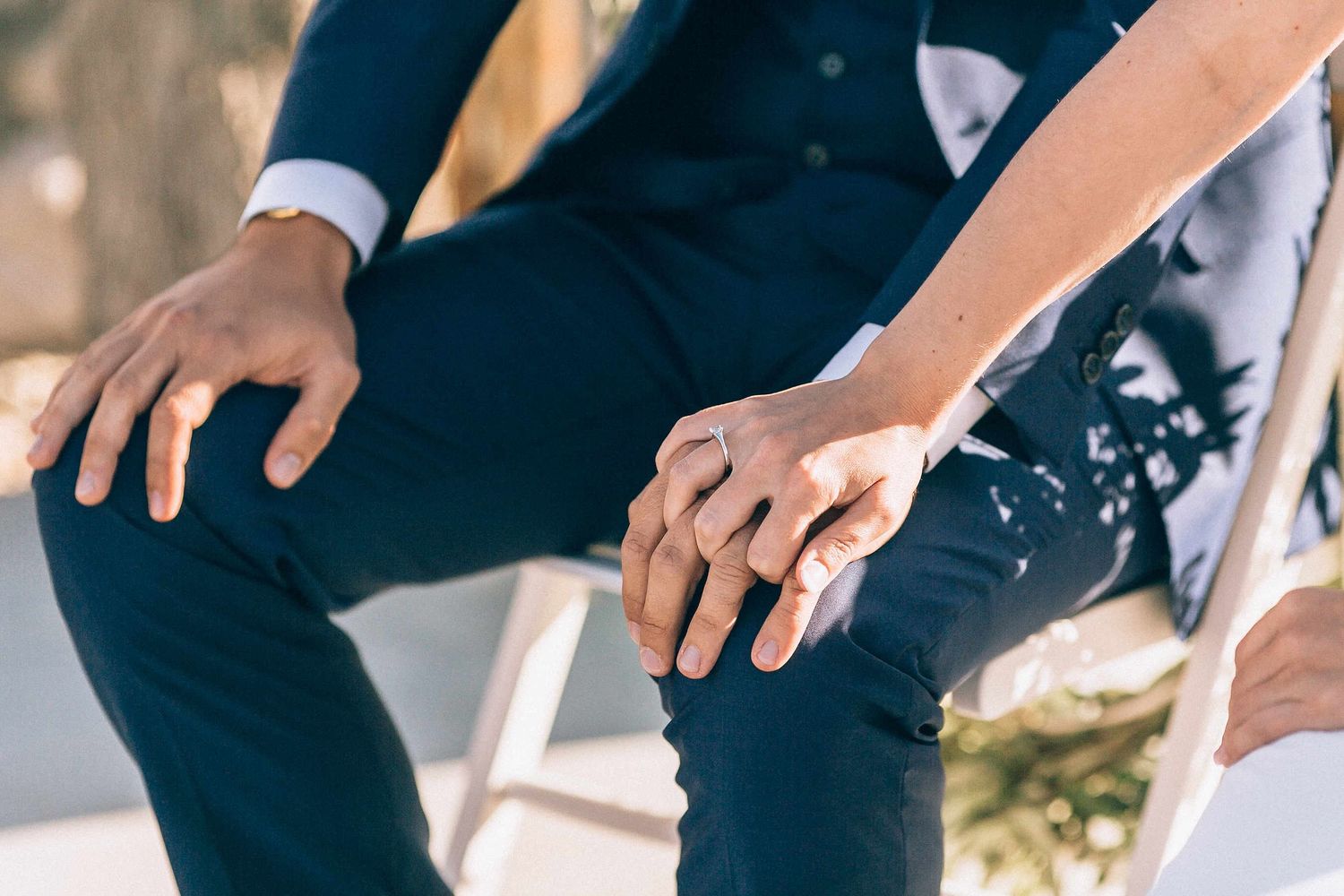 Close-up shot of the bride and groom holding hands tightly during their wedding vows