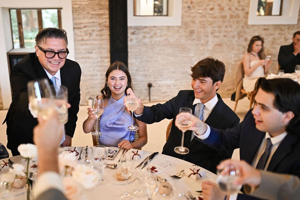 Joyful wedding guests toasting with champagne glasses, sharing happy emotions during a premium banquet at Finca del Canónigo, Valencia.