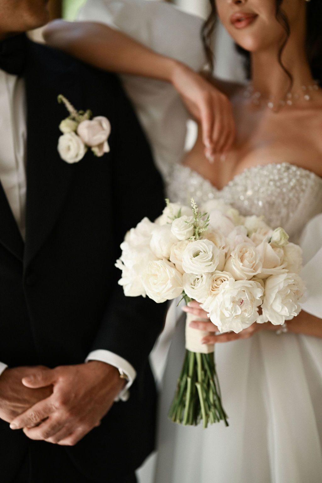 Close-up shot of the bride's hands with her bouquet and the groom's hands, showcasing the premium aesthetic of their wedding style.