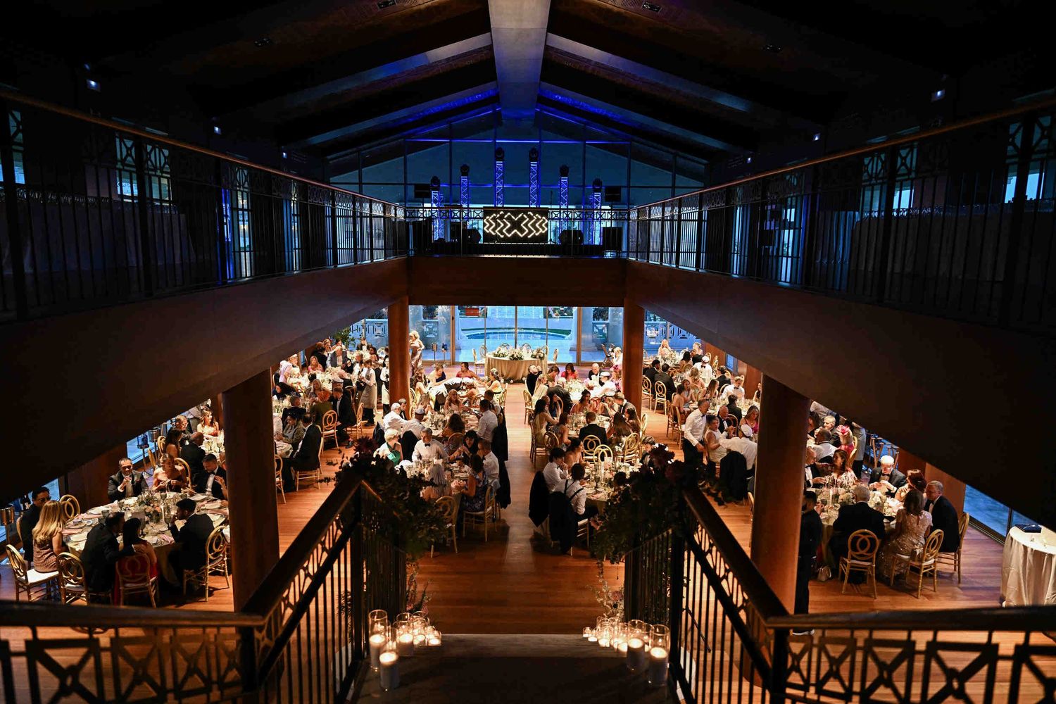 Overhead view of a luxury two-story wedding reception hall with lit tables and guests at Hotel Las Arenas.