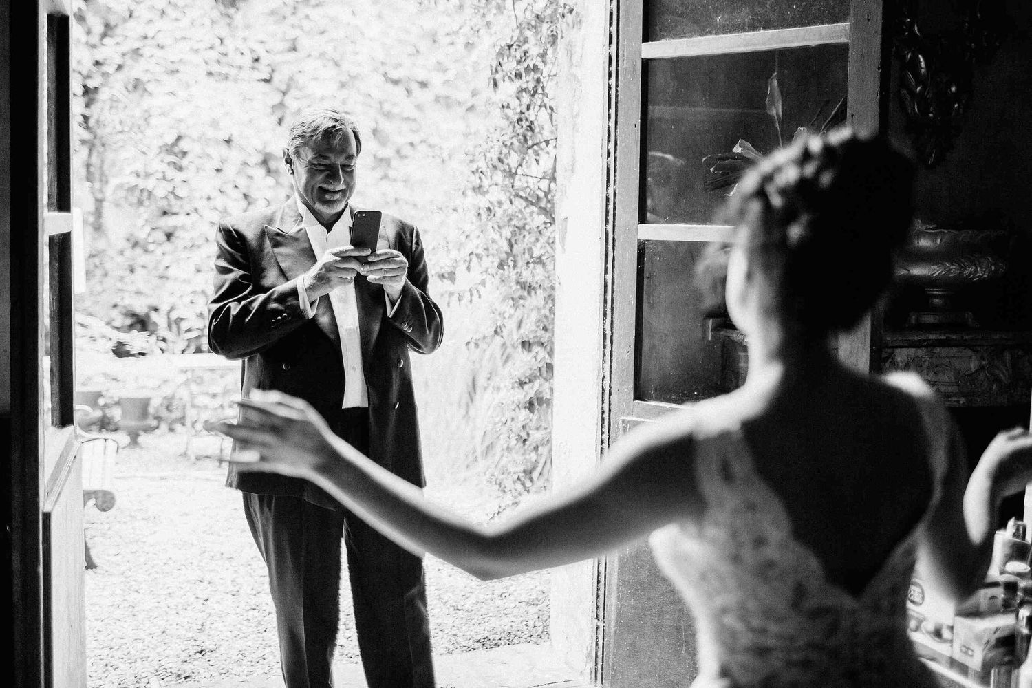 Candid moment of a father photographing his daughter during bride's preparations at Masia El Follo. Captured by wedding photographer in Barc