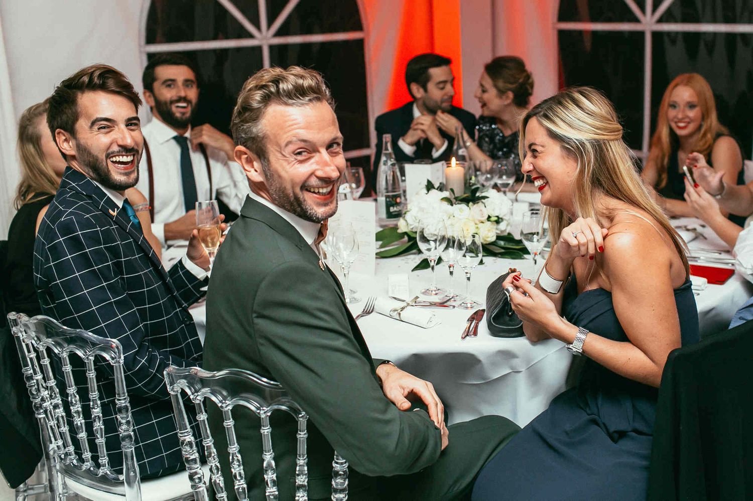 Stylish European guests looking at the camera during a wedding banquet. Captured by a professional reportage photographer.
