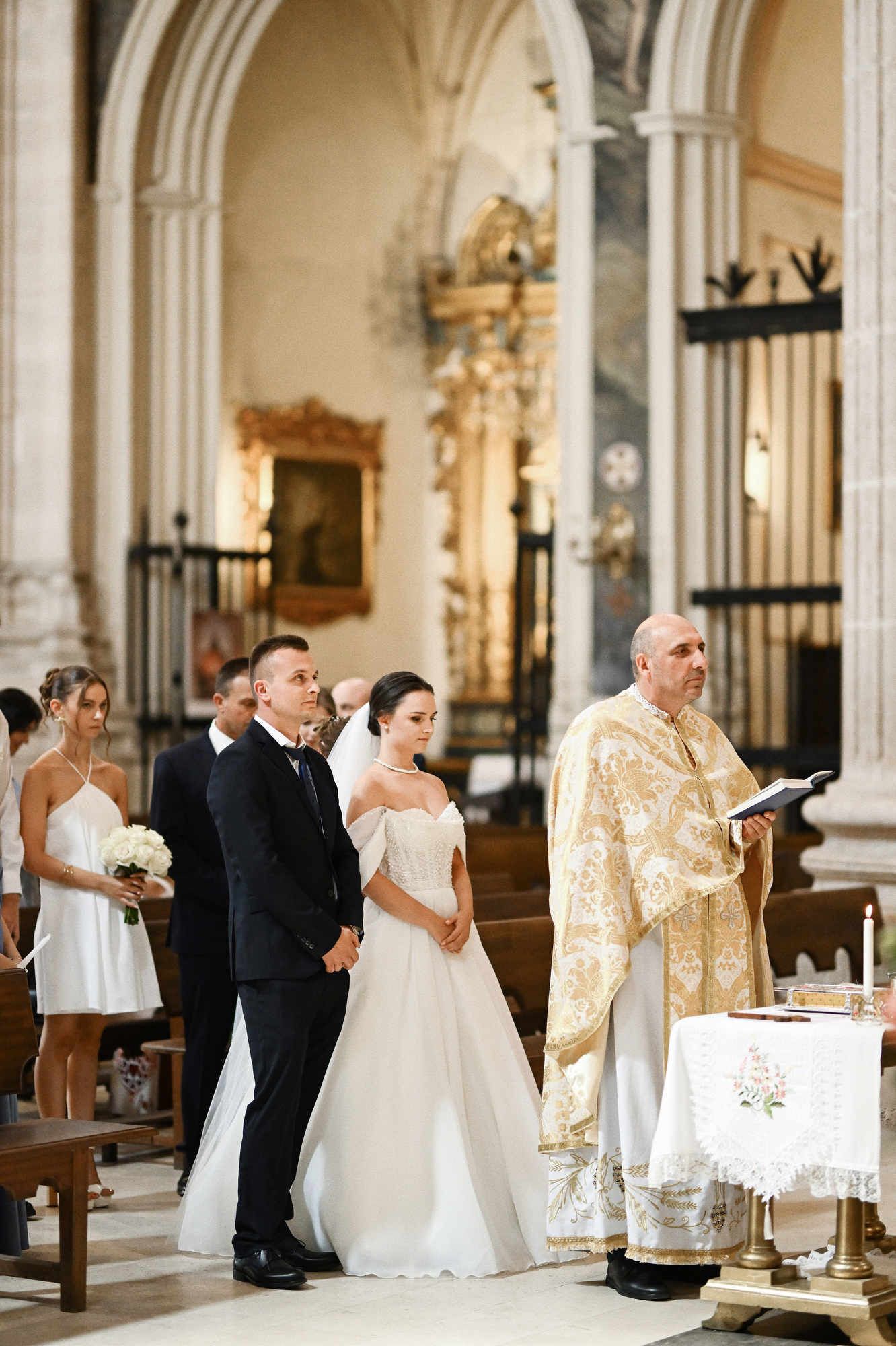 Editorial documentary wedding photography of a bride and groom standing behind the priest during a church ceremony in Valencia Region
