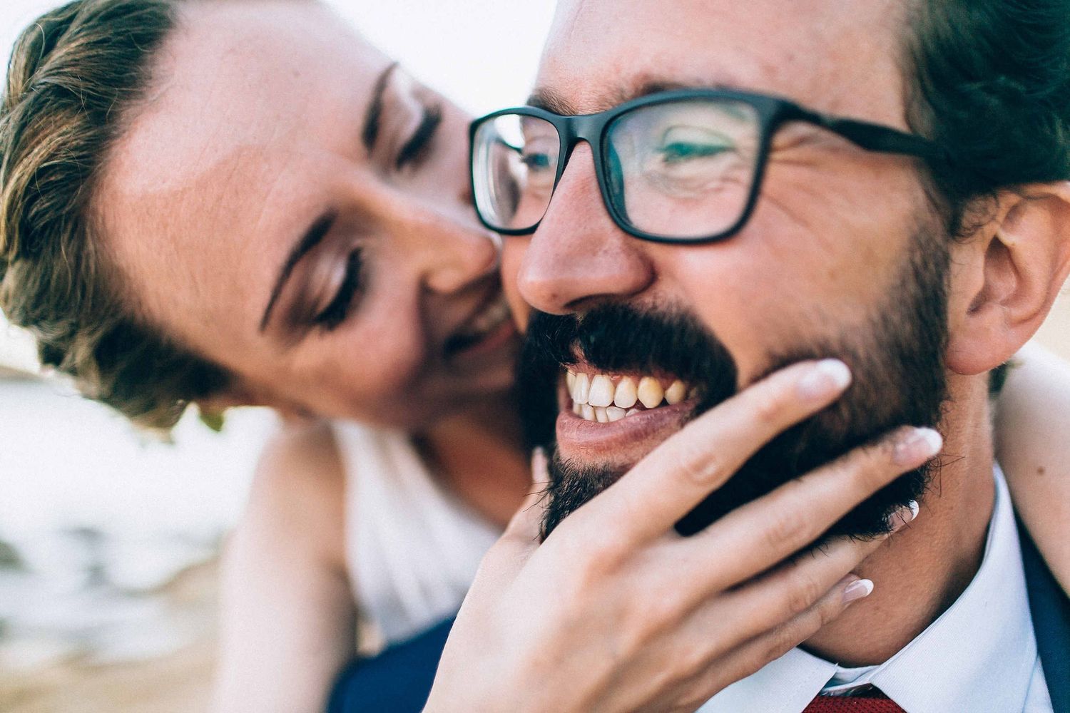 A playful and intimate moment where the bride touches the groom's beard.