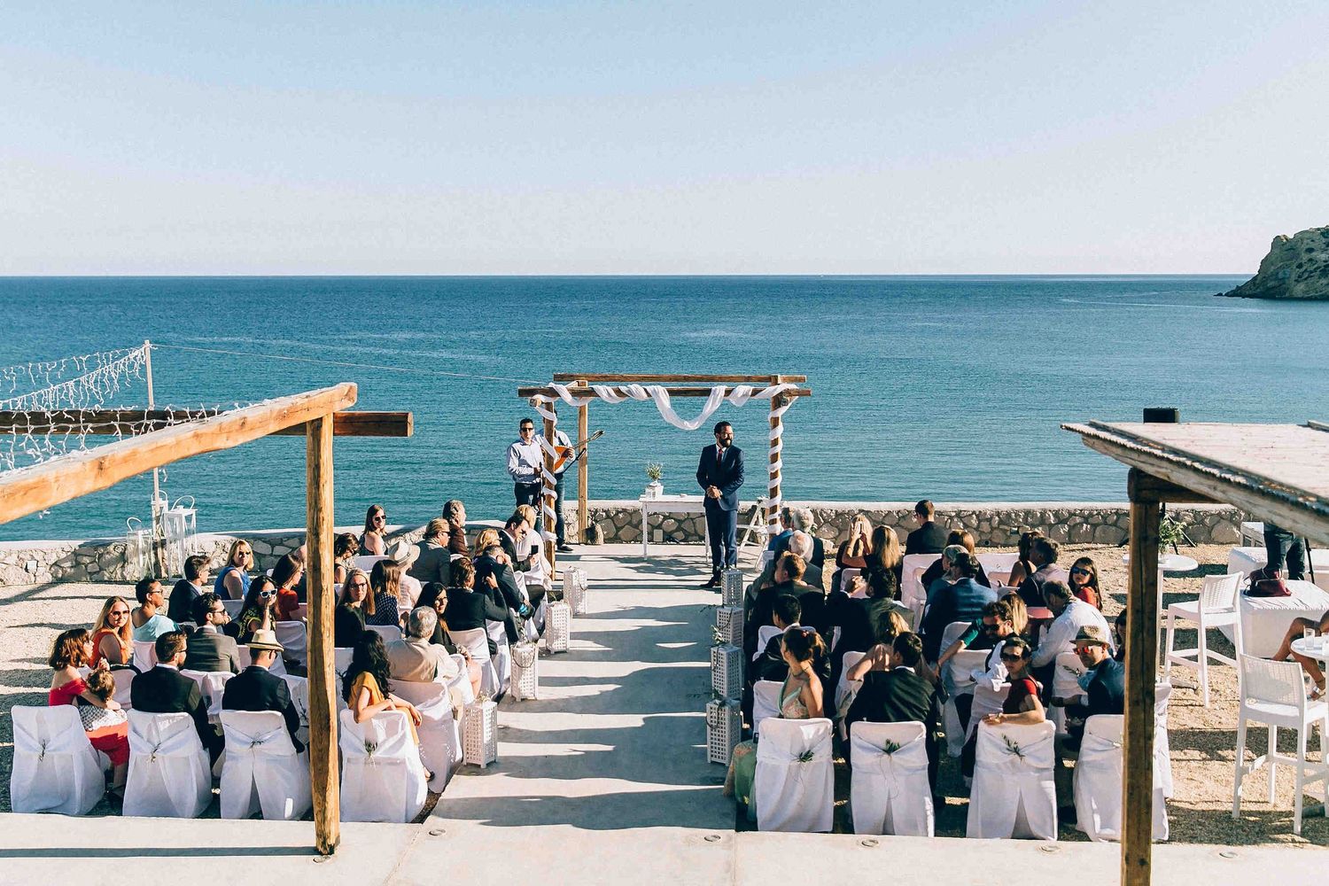 Panoramic view of the wedding ceremony setup in Milos overlooking the Mediterranean coastline