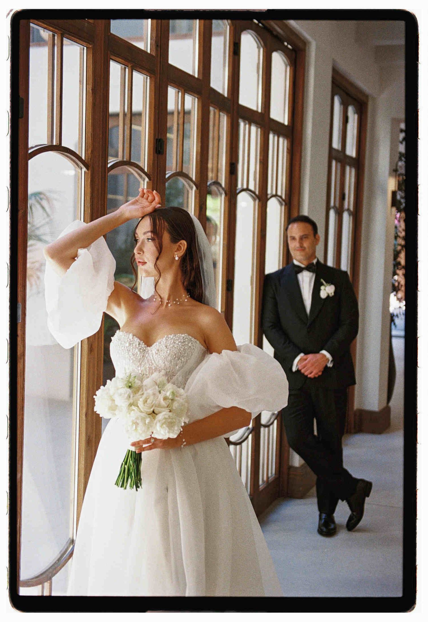 Editorial 35mm film portrait of a bride in a statement sleeve gown, with the groom admiring her at a Valencia wedding venue.