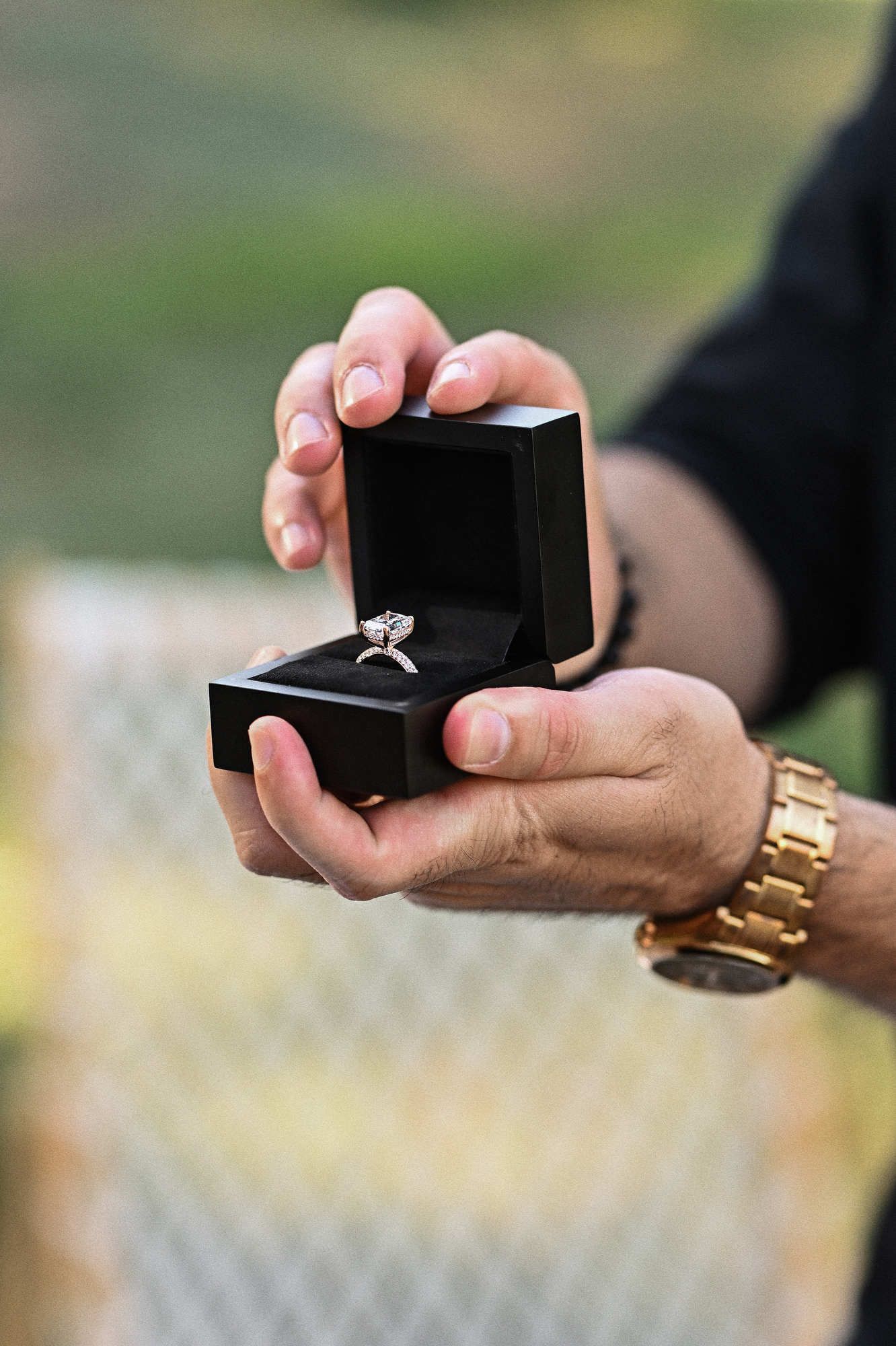 Man's hands opening a black box to reveal a sparkling diamond ring before a secret proposal in Valencia.