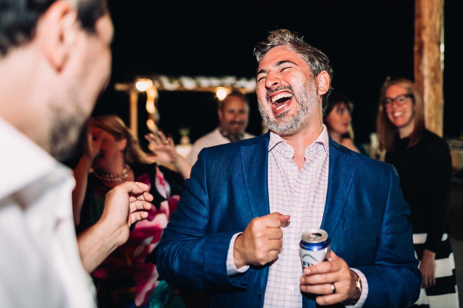 Hilarious and candid photo of wedding guests bursting with laughter while dancing.