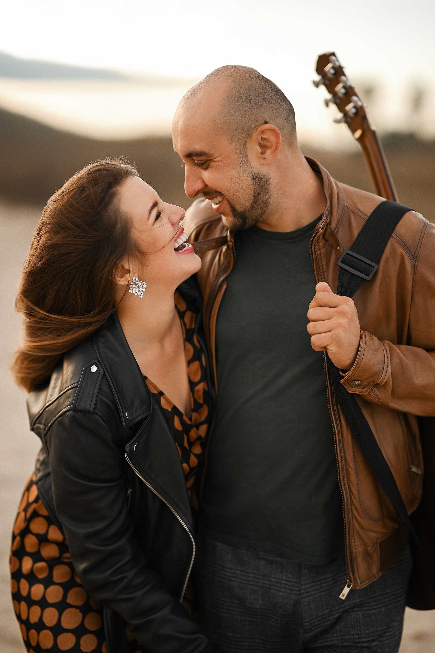 Couple walking on the sand and laughing during their Mediterranean beach engagement session in Valencia