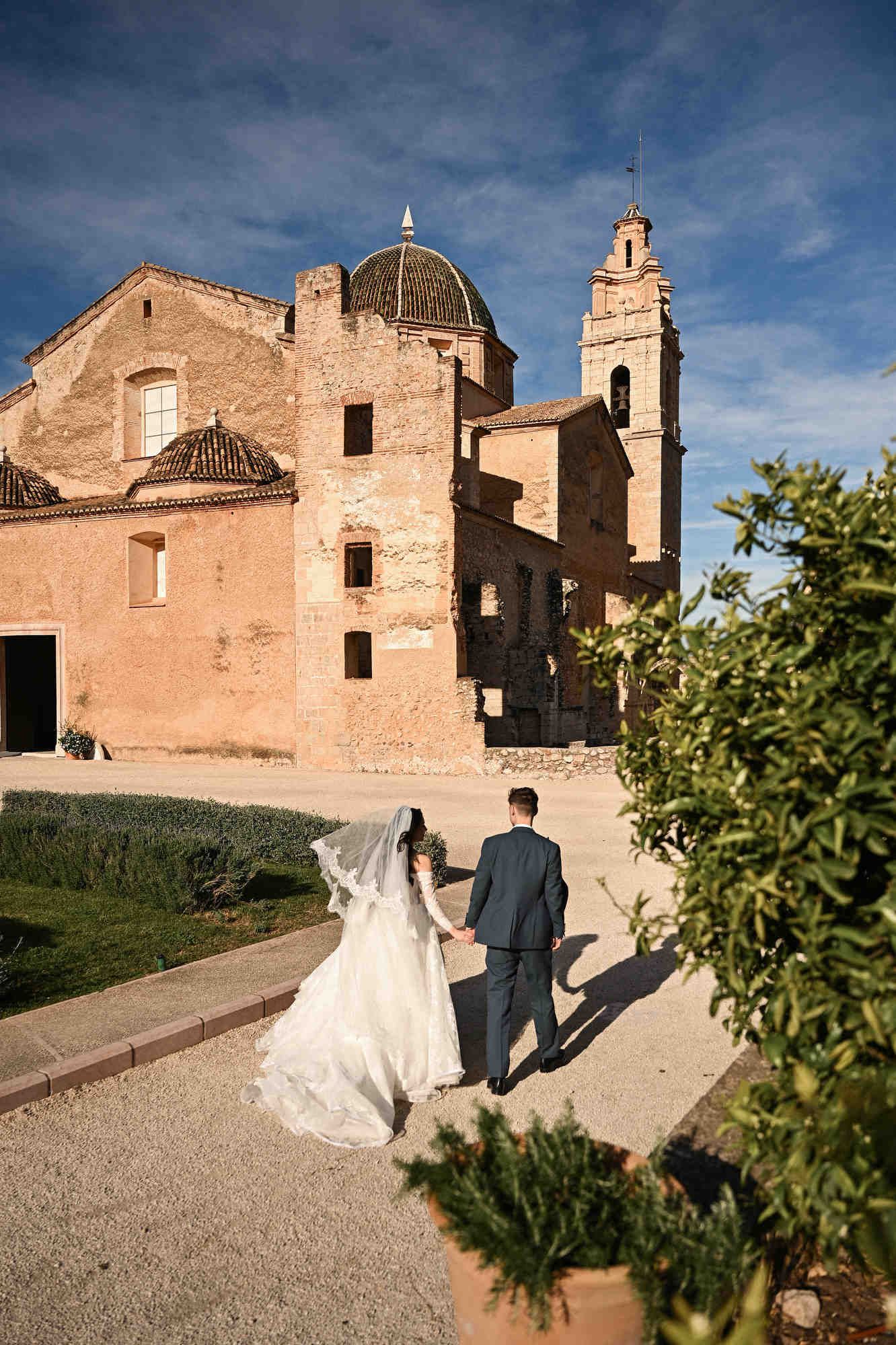Bride and groom exploring the deep architectural arches of the monastery during their wedding photosession in the Valencian countryside.