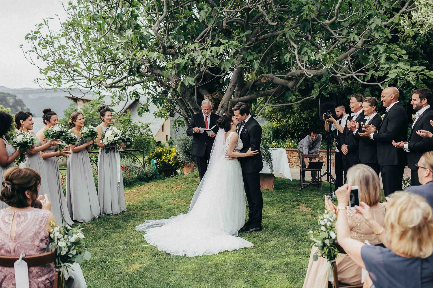 Wedding ceremony in Spain. An intimate outdoor ceremony under a tree with guests in a charming authentic Spanish village setting