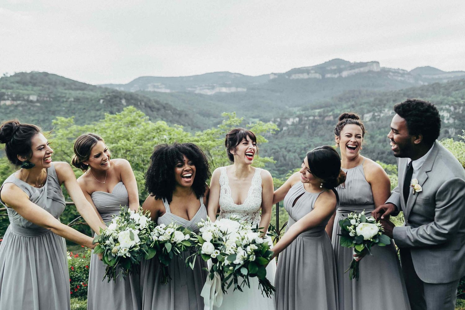 The bride and her bridesmaids posing with a breathtaking mountain view at a luxury Spanish villa. Editorial wedding photography in Catalonia