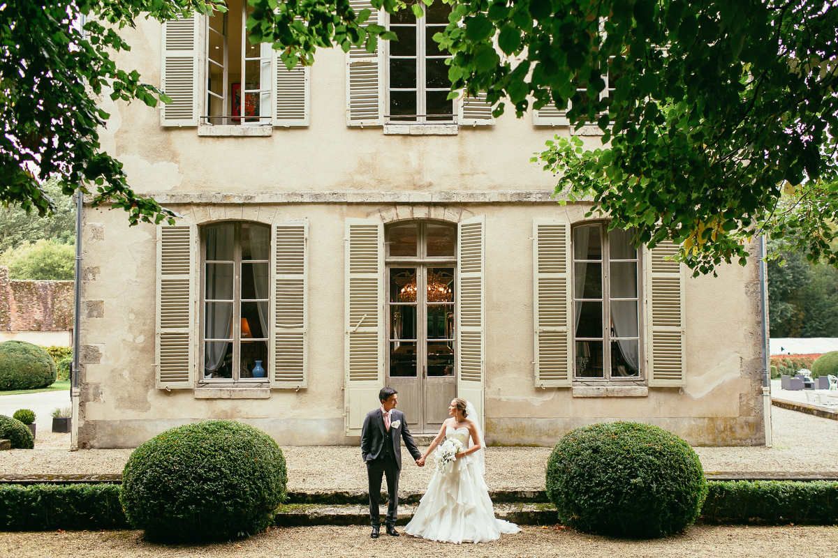 Destination wedding photographer near Paris captured this couple holding hands outside the facade of Chateau de Changy.